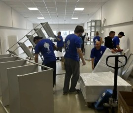 Группа сотрудников разбирает мебель и оборудование в помещении.