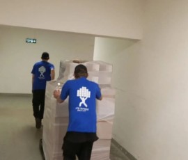 Двое сотрудников перемещают палету с упакованным грузом по коридору.